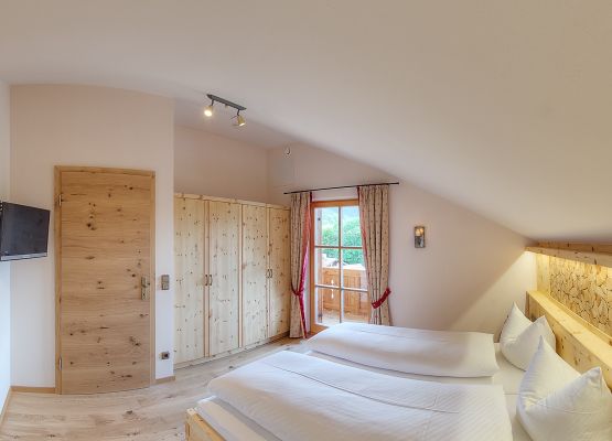 Schlafzimmer I mit maßgefertigter Zirbenholzausstattung, TV und Ostbalkon
